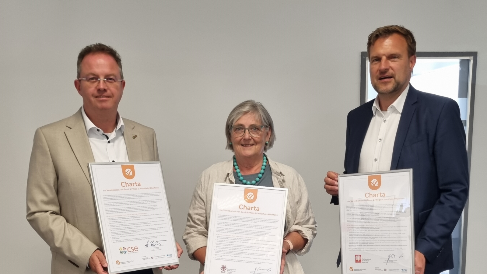 Dire Menschen mit Urkunden zum Beitritt zur Charta Vereinbarkeit Beruf und Pflege