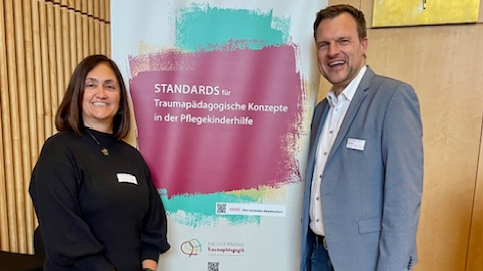 Sandra Dündar und Caritasdirektor Hermans stehen vor Roll up