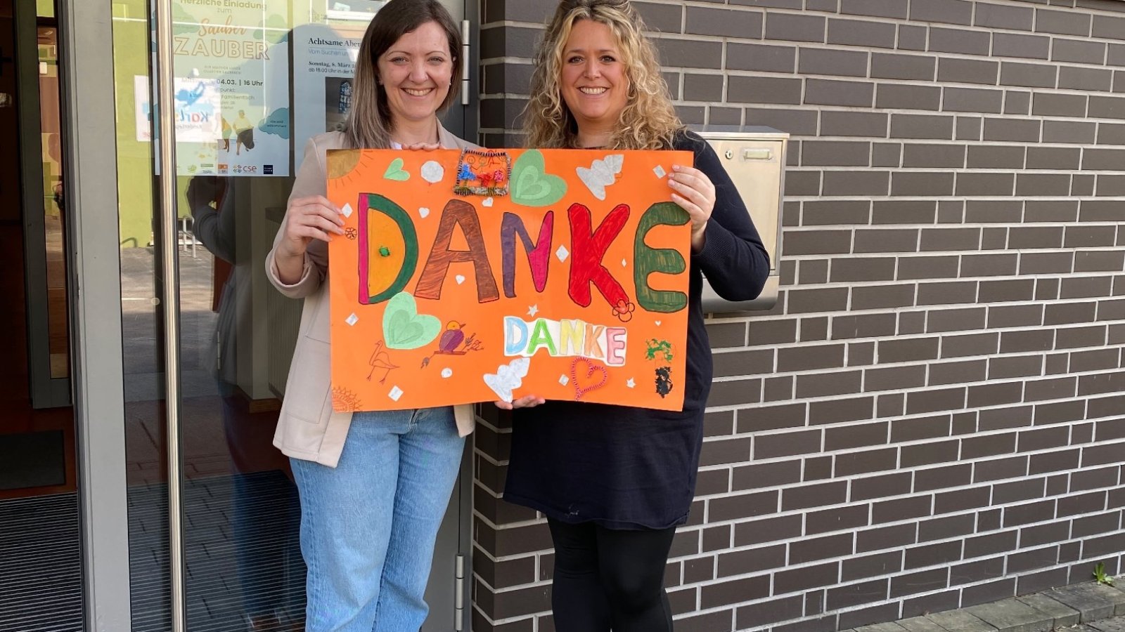 zwei Frauen halten ein Danke-Plakat