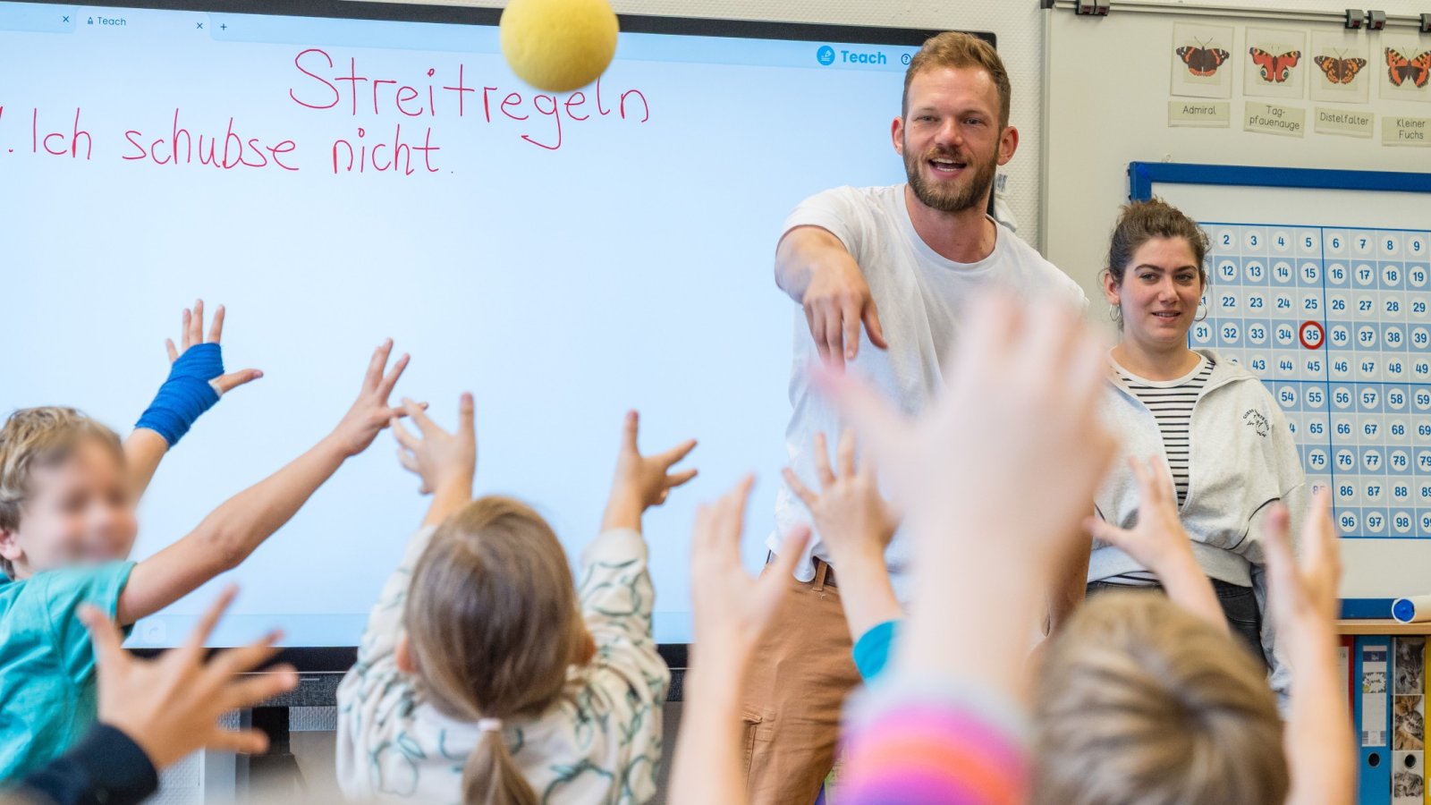 Zwei Personen werfen einen Ball zu einer Schulklasse