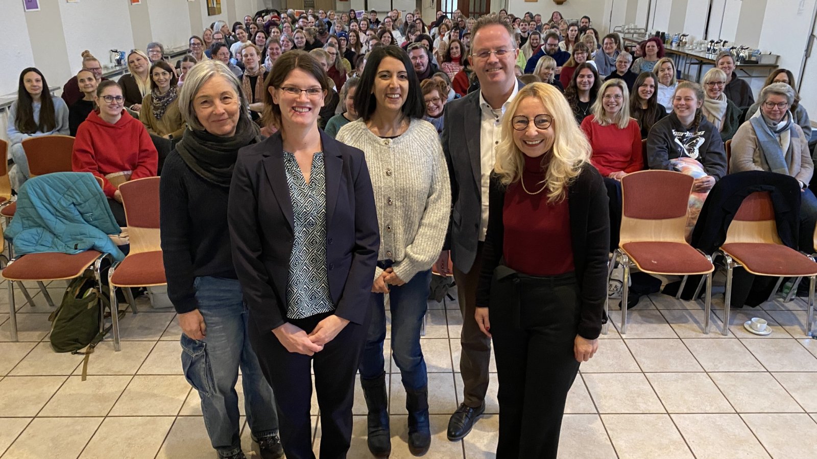 Leitungsteam und Referenten mit den Teilnehmenden im Hintergrund
