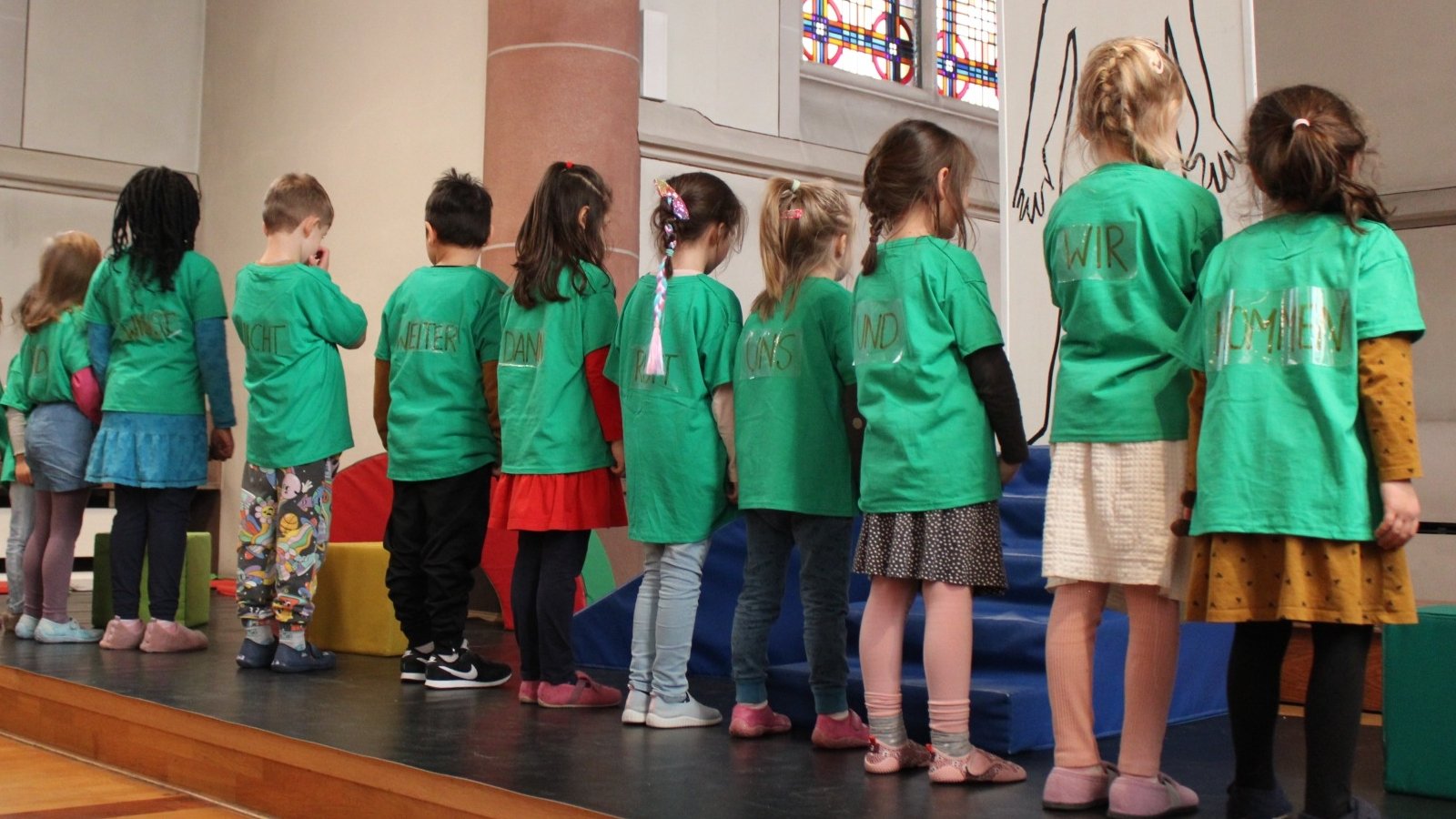 Kinder in Reihe stehend mit Rücken zur Kamera