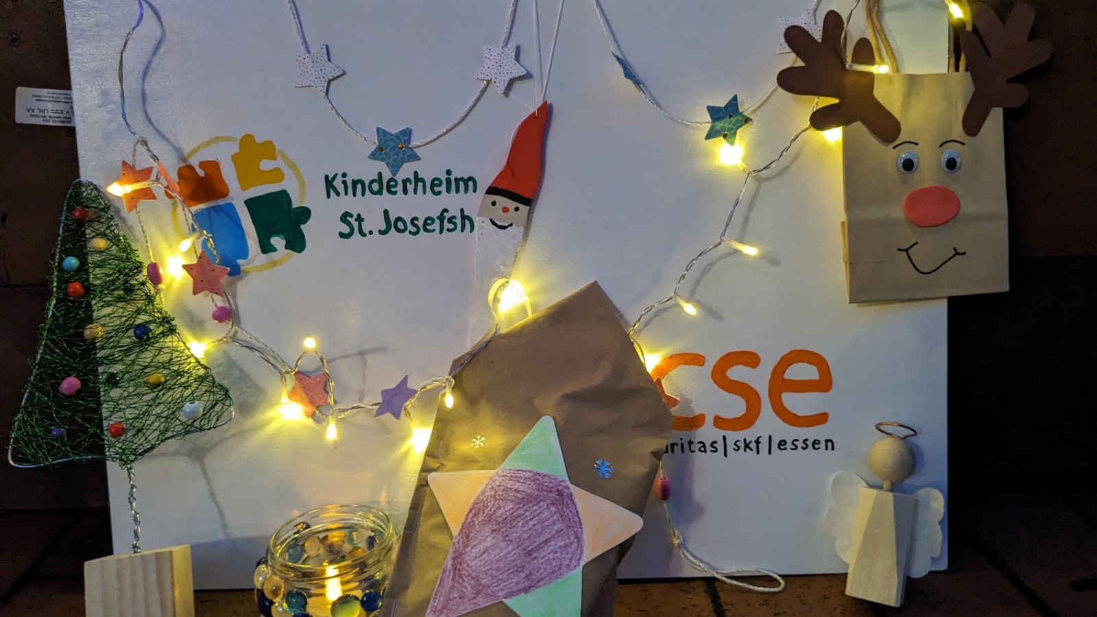 Kinderzeichnungen und Gebasteltes vor dem Kinderheim-Logo 