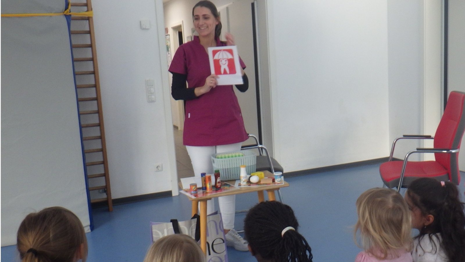 Kinder mit dem Rücken zur Kamera sitzend schauen Zahnärztin an 