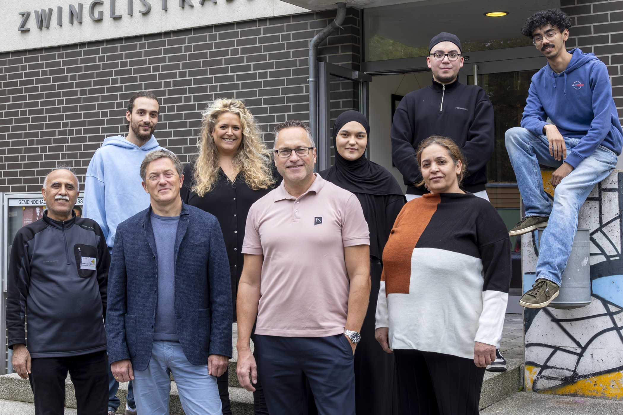 Neun Personen stehen vor einem Gebäude