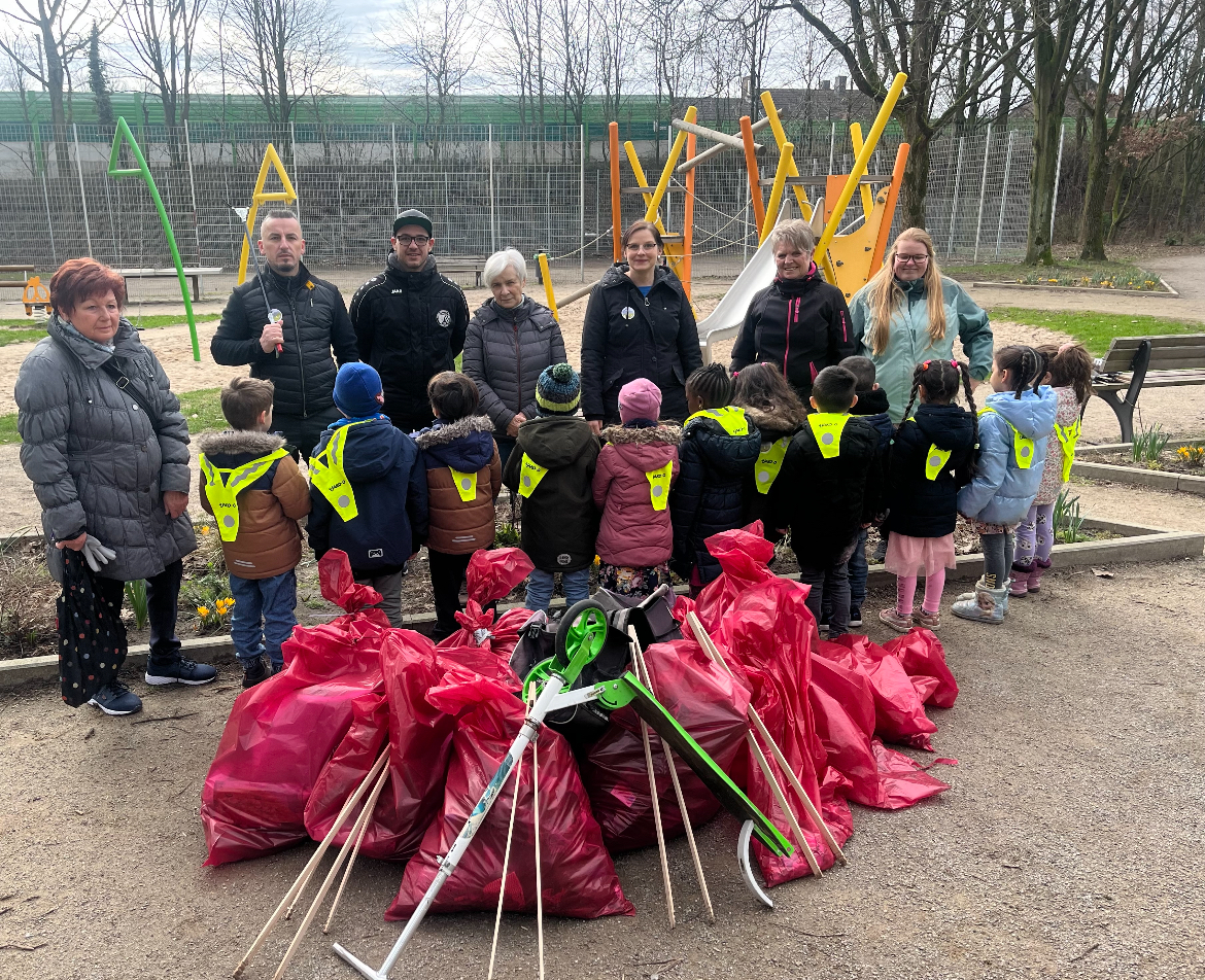 Kinder und Erwachsene auf dem Spielplatz am Meersternweg mit vollen Müllsäcken